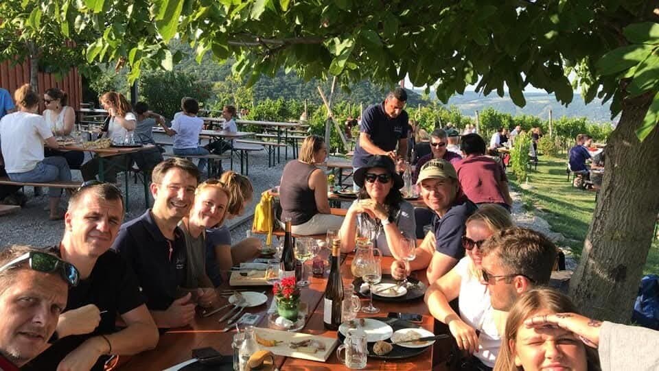 A long table of us under a tree at a wine tavern in the Austrian vineyards