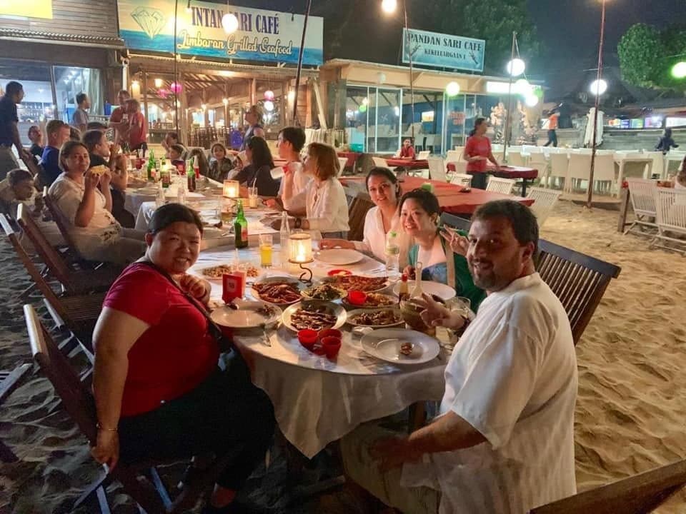 A long seafood dinner on the sand, at tables lit by candles