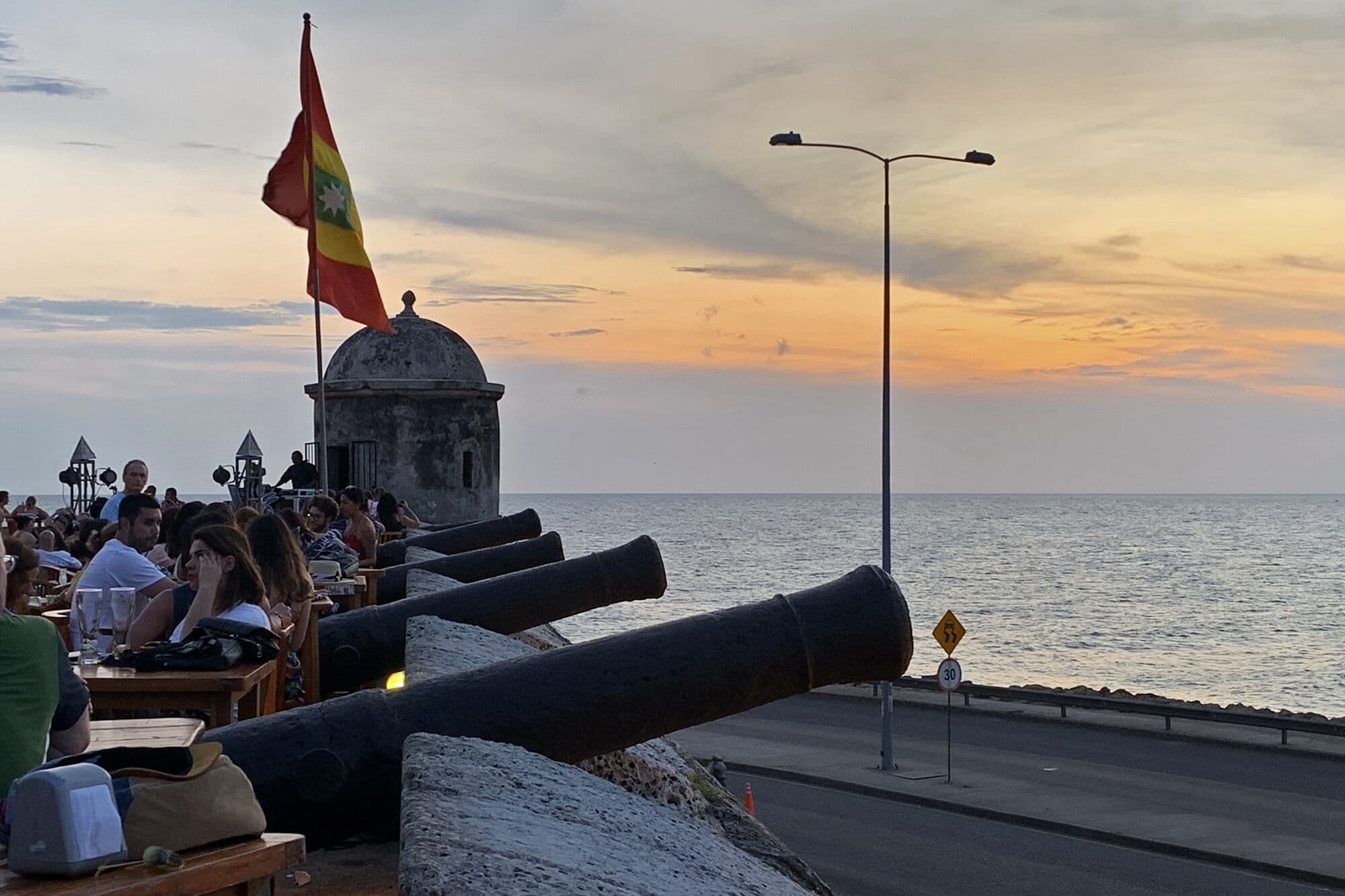 Sunset over the sea from the Santo Domingo bastion on Cartagena's city walls, with old cannons and the city flag