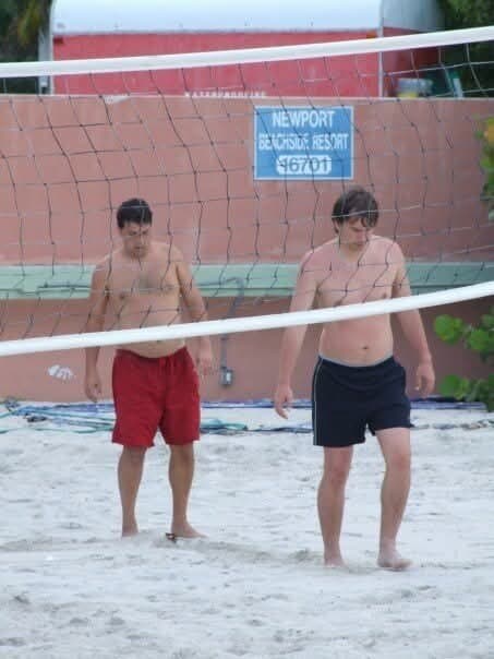 Two of us at a beach volleyball net, under a Newport Beachside Resort sign