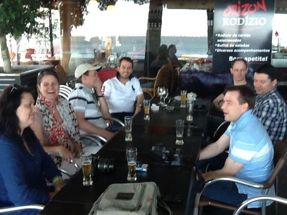 A table of us laughing over beers at a seaside rodízio
