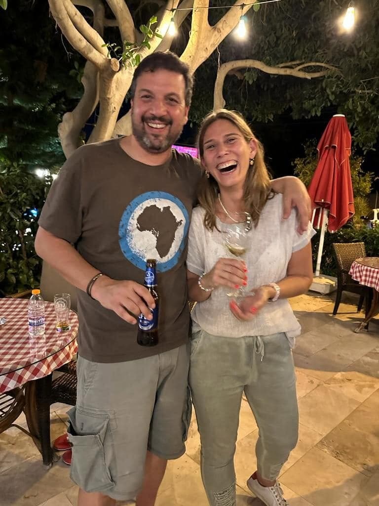 Two of us laughing under a tree strung with lights