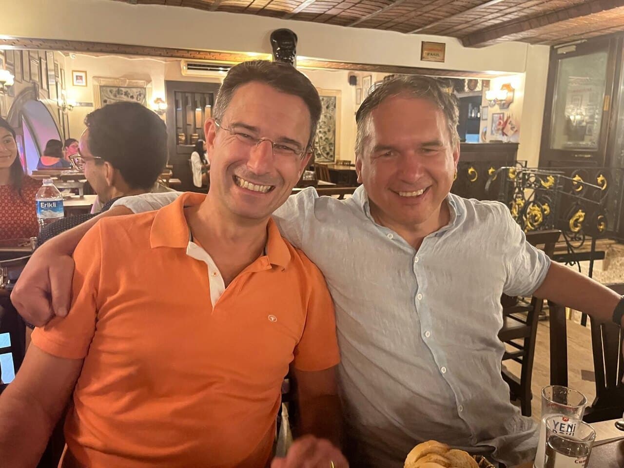 Two of us arm in arm at a restaurant table, grinning
